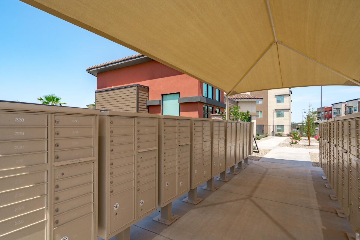 Rows of outdoor mailboxes under a canopy in a modern apartment complex.