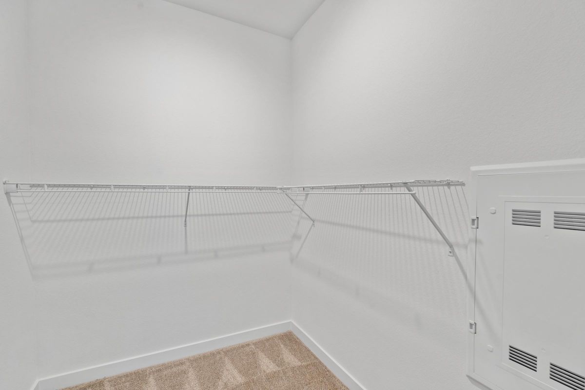 Empty white walk-in closet with beige carpet and wire shelf racks along two walls.