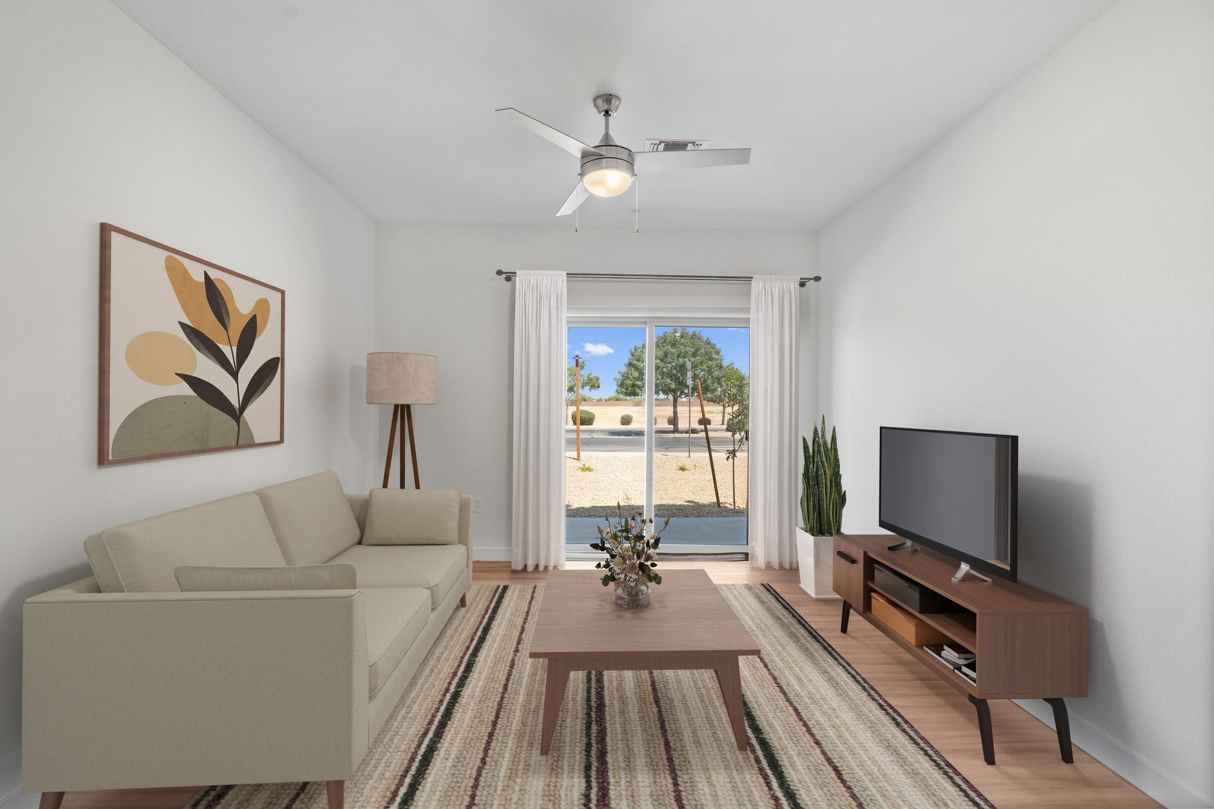 Minimalist living room with beige sofa, TV, coffee table, large window, and abstract wall art.